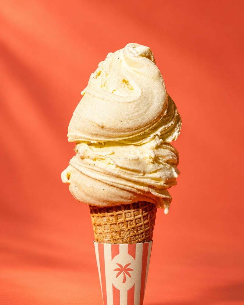A vanilla cone in a striped sleeve on coral